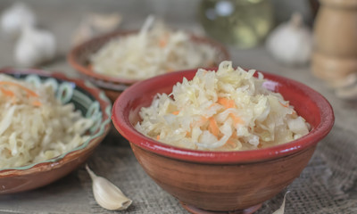 Homemade sauerkraut village. Fermented cabbage. Vegan salad rustic style glass jar or ceramic pottery bowl. Fermented food great for good health. Traditional rustic winter food.