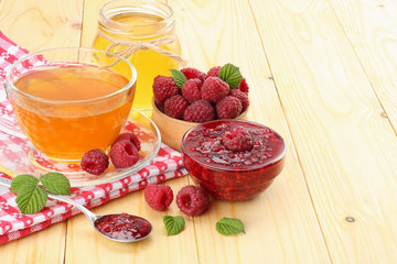 healthy background. raspberry with raspberry jam, honey and tea on light wooden background.