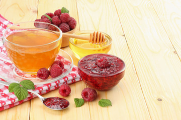 healthy background. raspberry with raspberry jam, honey and tea on light wooden background.