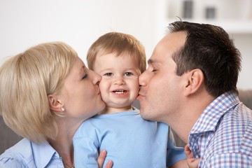 Father and mother kissing baby boy