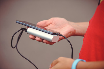 the man is holding the phone and the charger. Powerbank and smartphone in hand. Power-saving device power bank smartphone