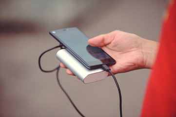 the man is holding the phone and the charger. Powerbank and smartphone in hand. Power-saving device power bank smartphone