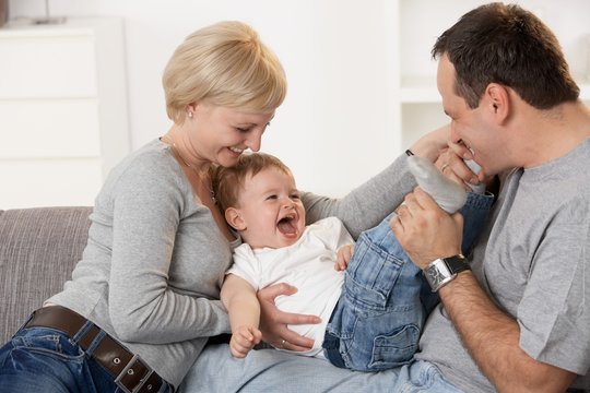 Happy caucasian couple playing with baby