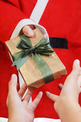 Santa Claus holding and offering a gift on his hand.