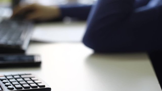 A couple of male co-workers working in the office, using computers.