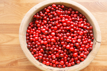 Top view of bright red berries in a wooden bowl. Ripe berries on a wooden background