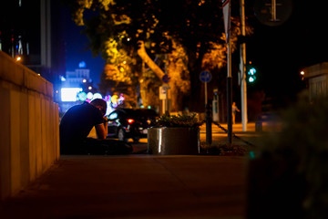 sad guy sits on the background of the evening city