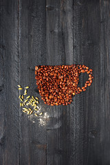 Cup made of coffee beans with cardamon on the black wooden table