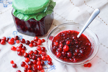 Jam in a bowl, berries and a jar of jam on a white tablecloth