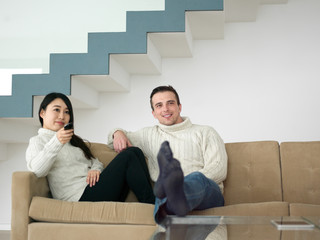 multiethnic couple on the sofa watching television