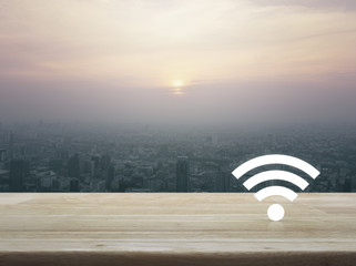 Wi-fi button on wooden table over city tower at sunset, vintage style, Technology and internet concept