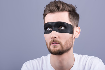 Obraz premium Beauty portrait of a man. A young man with a black strip on the eyes, makeup