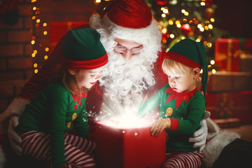 Fototapeta na wymiar Santa Claus and little elves with magic gift for Christmas