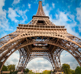 Fototapeta na wymiar The eiffel tower viewed from te bottom on a sunny day with white clouds. This is the iconic building that symbolises France in the world.