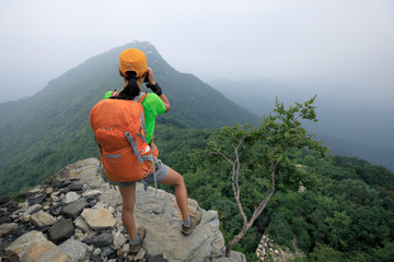 Obraz premium woman hiker taking photo on the top of mountain