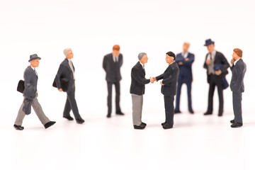 miniature businessmen handshaking on white background