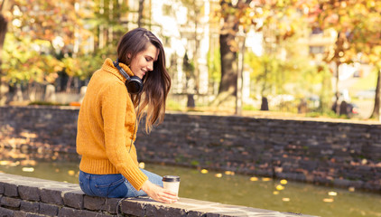 Young woman with coffee in the autumn park