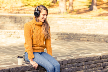 Autumn woman drinking coffee and listening music