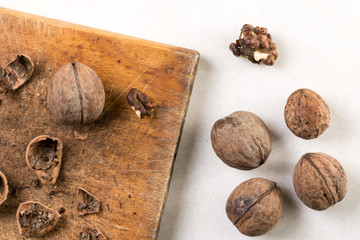 Wooden board and walnuts for cleaning above white marble background table