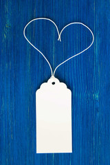 White blank paper price tag or label set on the blue wooden background, closeup.