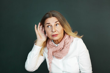 Frustrated elderly woman suffering from deafness, trying hard to hear something. Curious senior...