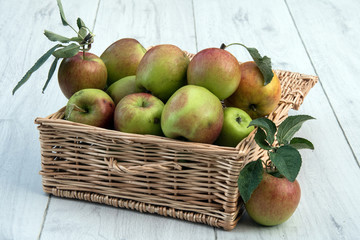 Fresh apples with stalks in a wicker basket.