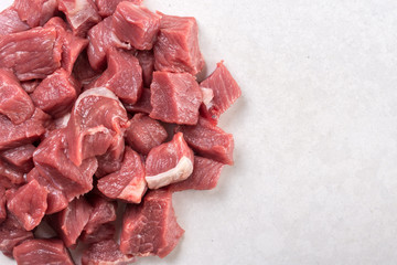 Flat lay above chopped raw beef steak on the white marble background with copy space