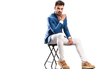 seated fashion man touching his face with finger