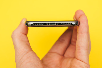 Holding a new smartphone, isolated on yellow background