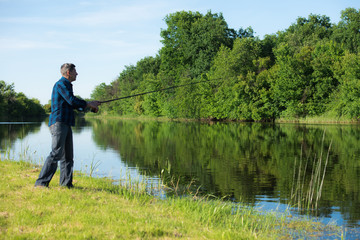 Fototapeta na wymiar Hobby fisherman is fishing at the river bank