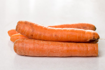 Fresh raw dirty carrot from the garden on the white marble background