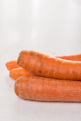 Fresh raw dirty carrot from the garden on the white marble background