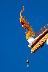Fototapeta na wymiar A detail of northern thai temple roof ,Naga , under clear blue sky