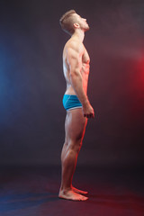 Bodybuilding, sports, weightlifting, fitness concept. Side view of young muscular fit man with perfect body, vertical image.