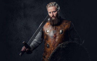 Fototapeta na wymiar Viking dressed in Nordic armor holds a shield and silver sword.