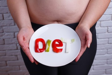 Word diet carved of vegetables on the plate in hands of overweight  unrecognizable woman. Diet, nutrition, healthy food, fit lifestyle concept