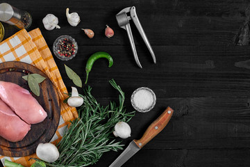 Raw chicken breast and condiments in a rustic wooden setting, top view