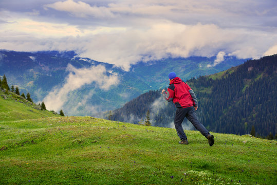 Traveler runs through the green alpine meadow