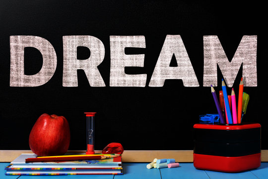 Text dream on black chalkboard with school accessories