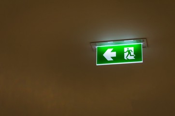 green emergency fire exit sign on ceiling in office building or shopping mall