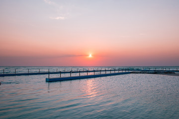 Obraz premium Sunrise of hazy sky by ocean pool.