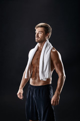 Fototapeta premium Portrait of a fitness man with towel on shoulders looking away. Happy young man relaxing after training.