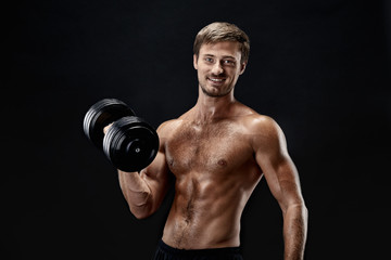 Fototapeta na wymiar Cropped horizontal shot of a young fit bodybuilder exercising with dumbbells posing on black background
