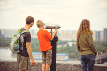 tourist looks at the city through binoculars