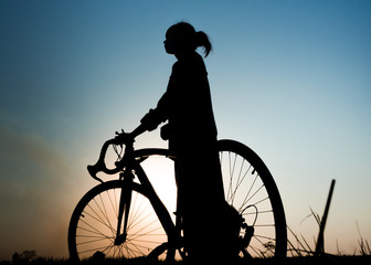 Fototapeta na wymiar silhouette of young woman with bicycle on sunset background.