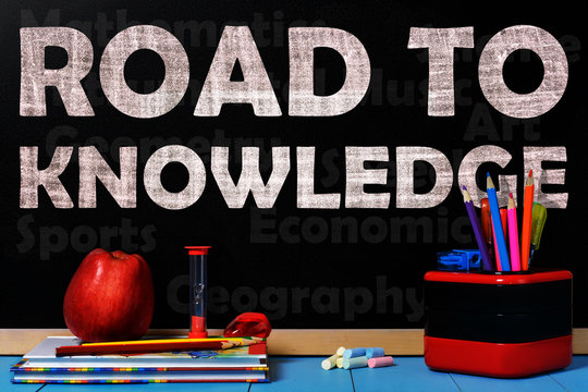 Text Road to knowledge on black chalkboard with school accessories