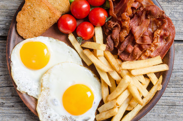 Breackfast : french fries , bacon and fried eggs