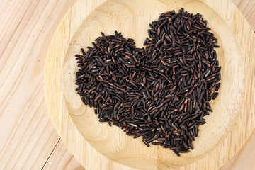 Close-up brown rice or riceberry organic food in bowl healthy on wood texture