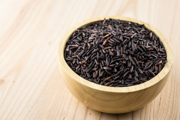 Close-up brown rice or riceberry organic food in bowl healthy on wood texture