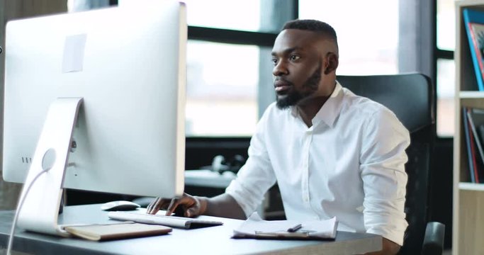 Young black man working use computer in office smiling technology african american businessman casual communication entrepreneur male successful person portrait smart business Slow Motion Shot